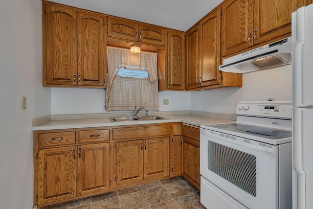 kitchen with brown cabinets, a sink, under cabinet range hood, white appliances, and light countertops