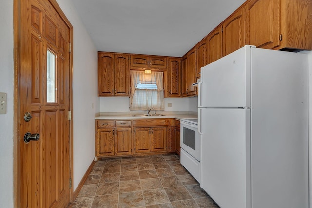 kitchen featuring baseboards, light countertops, brown cabinets, white appliances, and a sink