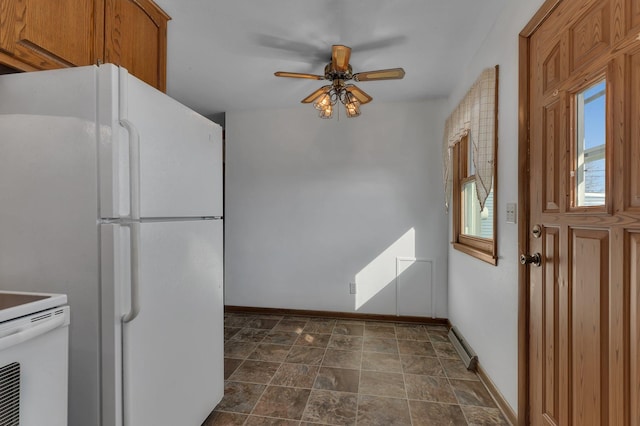 kitchen featuring ceiling fan, baseboards, freestanding refrigerator, brown cabinetry, and range