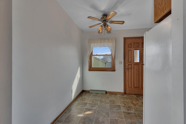 entryway with stone finish floor, a ceiling fan, and baseboards