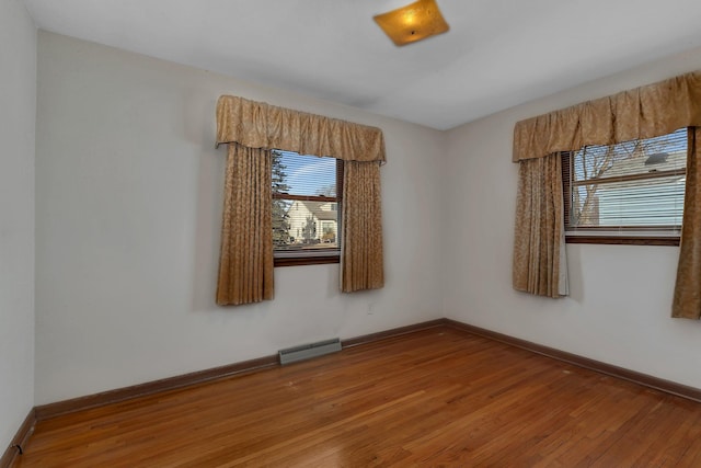 unfurnished room featuring visible vents, baseboards, and hardwood / wood-style floors