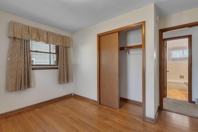 unfurnished bedroom with light wood finished floors, baseboards, and a closet