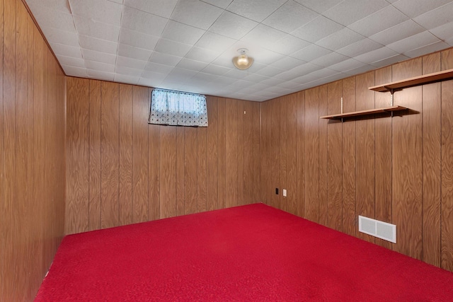 basement featuring visible vents and wood walls