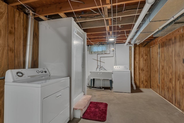 unfinished basement featuring washing machine and dryer, wood walls, and a sink