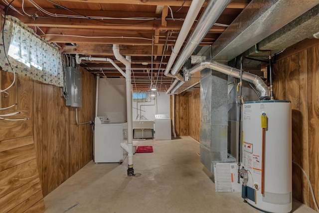 unfinished below grade area featuring electric panel, gas water heater, independent washer and dryer, and wood walls