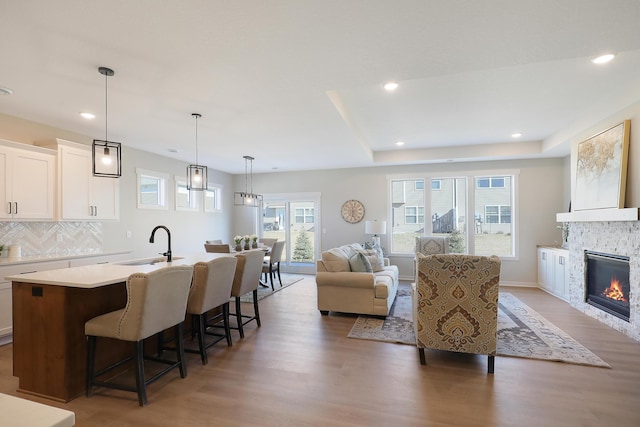 living area featuring light wood-type flooring, a stone fireplace, baseboards, and recessed lighting