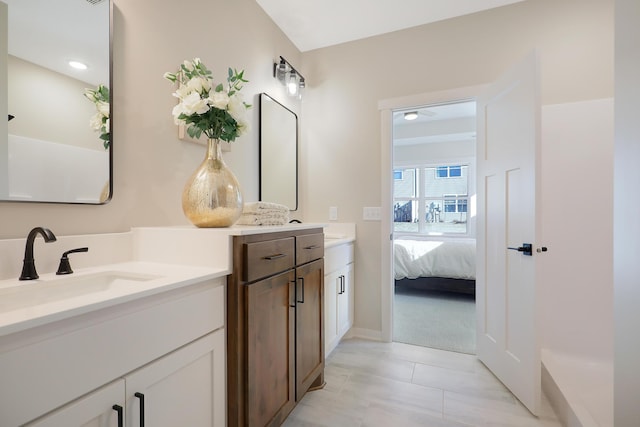 ensuite bathroom featuring tile patterned flooring, two vanities, a sink, and ensuite bath