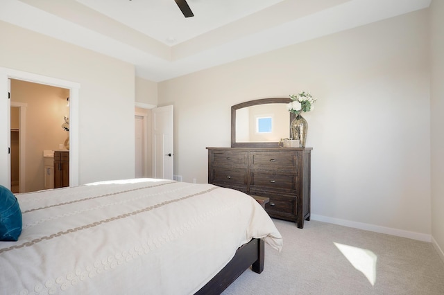 bedroom with light carpet, baseboards, ensuite bath, ceiling fan, and a tray ceiling