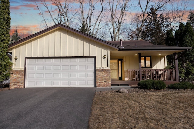 single story home with brick siding, covered porch, driveway, and a garage