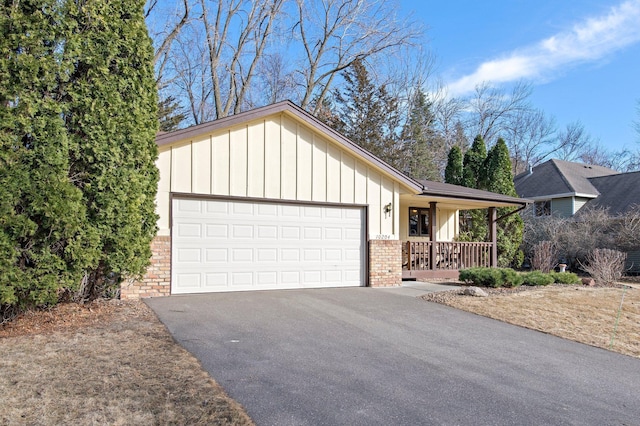 ranch-style house with brick siding, board and batten siding, a porch, a garage, and driveway