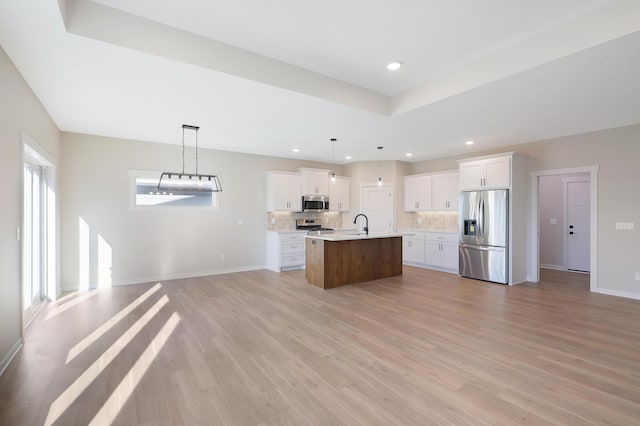 kitchen with appliances with stainless steel finishes, open floor plan, backsplash, and light countertops