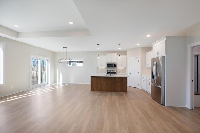 kitchen with decorative backsplash, open floor plan, stainless steel appliances, light countertops, and a sink