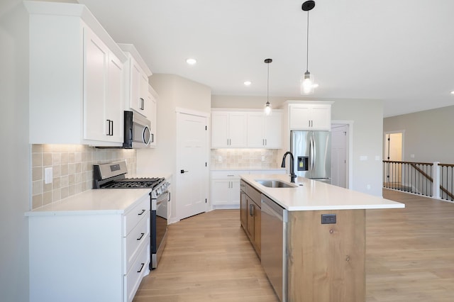 kitchen featuring appliances with stainless steel finishes, a kitchen island with sink, light countertops, light wood-type flooring, and a sink