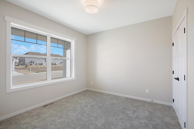 carpeted spare room with visible vents and baseboards