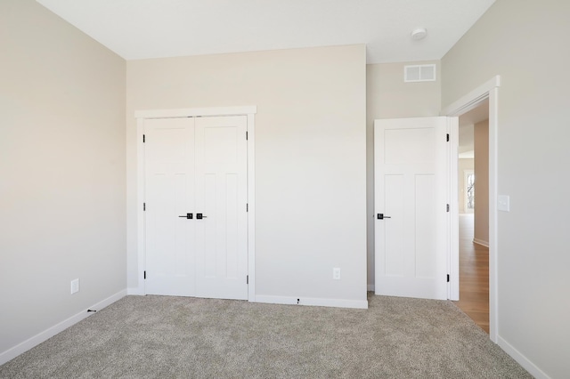 unfurnished bedroom featuring a closet, carpet flooring, visible vents, and baseboards