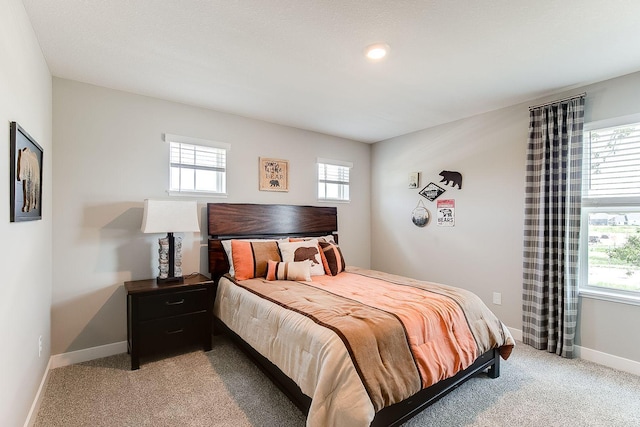 bedroom featuring multiple windows, light colored carpet, and baseboards