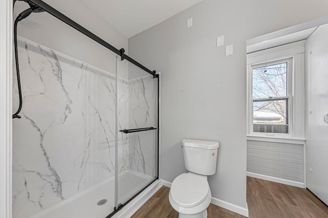 full bathroom featuring toilet, a marble finish shower, baseboards, and wood finished floors