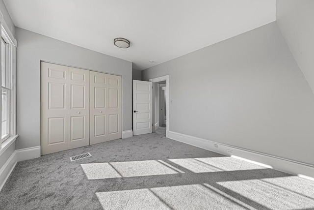 unfurnished bedroom featuring a closet, carpet, visible vents, and baseboards