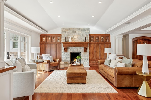 living area with decorative columns, lofted ceiling, and wood finished floors