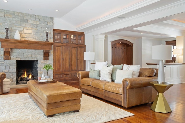 living area featuring wood finished floors, a fireplace, arched walkways, and vaulted ceiling