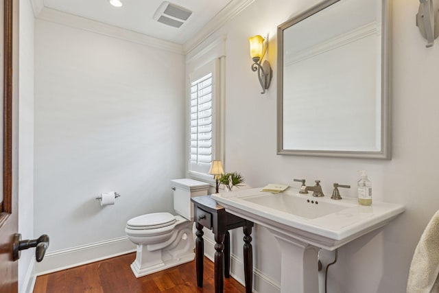 half bath featuring visible vents, toilet, ornamental molding, wood finished floors, and baseboards