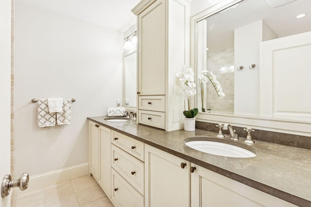 full bathroom featuring tile patterned flooring, double vanity, baseboards, and a sink