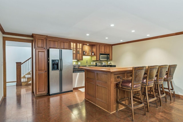 kitchen featuring ornamental molding, recessed lighting, appliances with stainless steel finishes, brown cabinetry, and baseboards