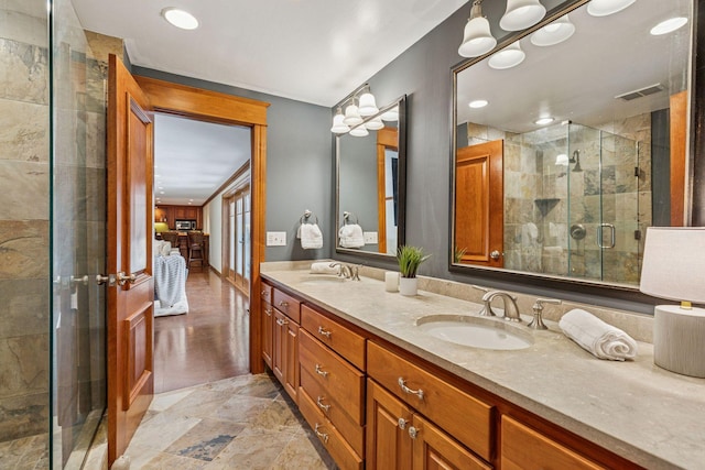 bathroom featuring double vanity, a stall shower, visible vents, and a sink