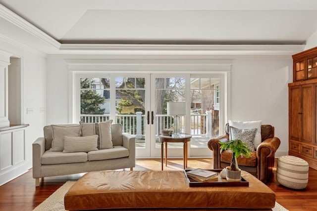 living room featuring a wealth of natural light, ornamental molding, a tray ceiling, and wood finished floors