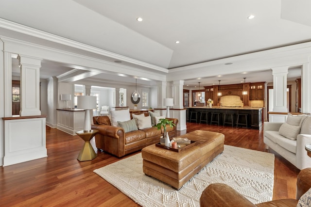 living room featuring vaulted ceiling, dark wood finished floors, crown molding, and ornate columns