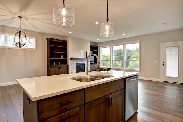 kitchen with a stone fireplace, recessed lighting, a sink, dishwasher, and dark wood finished floors