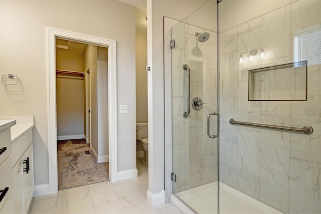 bathroom featuring marble finish floor, a spacious closet, toilet, a shower stall, and baseboards