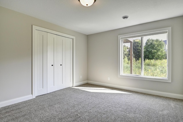 unfurnished bedroom with carpet floors, a closet, and baseboards