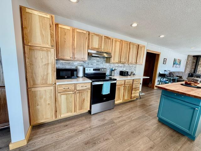 kitchen featuring light wood finished floors, decorative backsplash, stainless steel electric range, under cabinet range hood, and black microwave