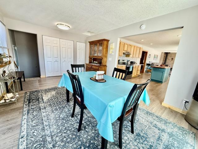 dining area with light wood-style floors, a textured ceiling, and baseboards