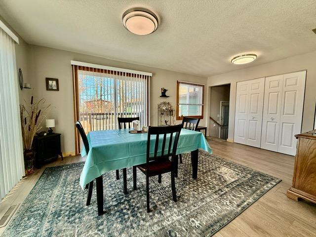 dining room with visible vents, a textured ceiling, and wood finished floors