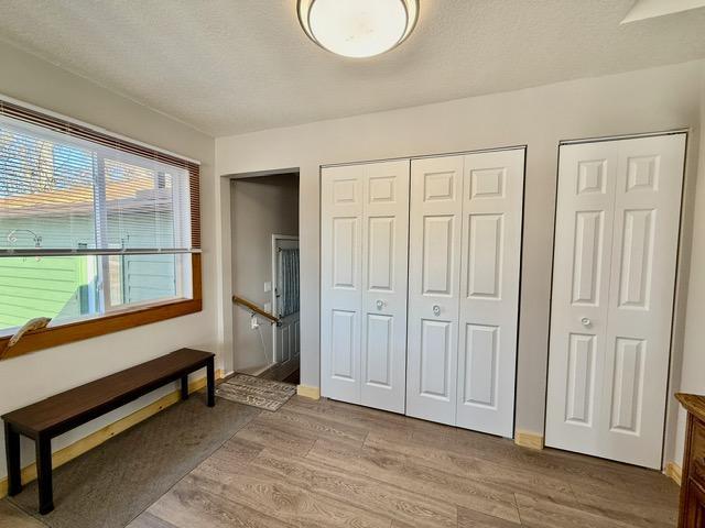 bedroom featuring light wood-type flooring, two closets, and a textured ceiling