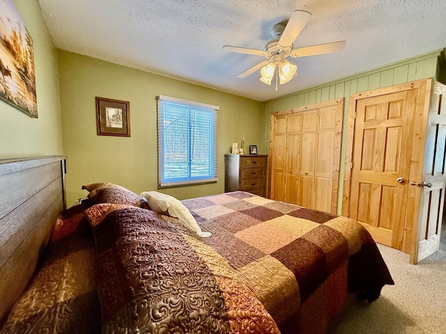 carpeted bedroom with multiple closets, ceiling fan, and a textured ceiling