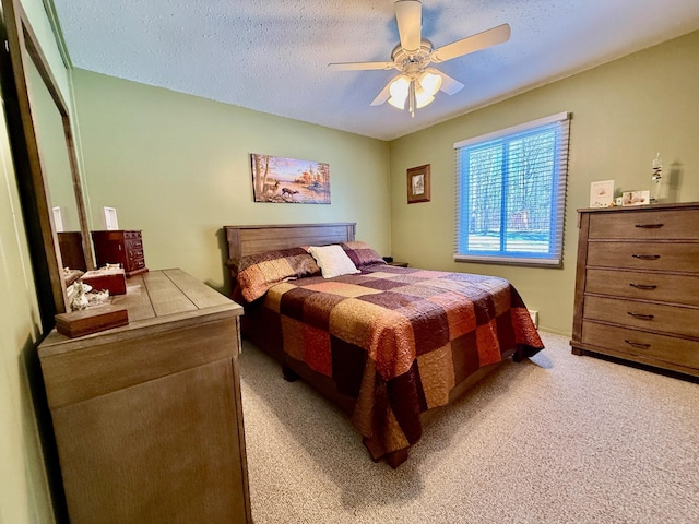 bedroom with light colored carpet, ceiling fan, and a textured ceiling