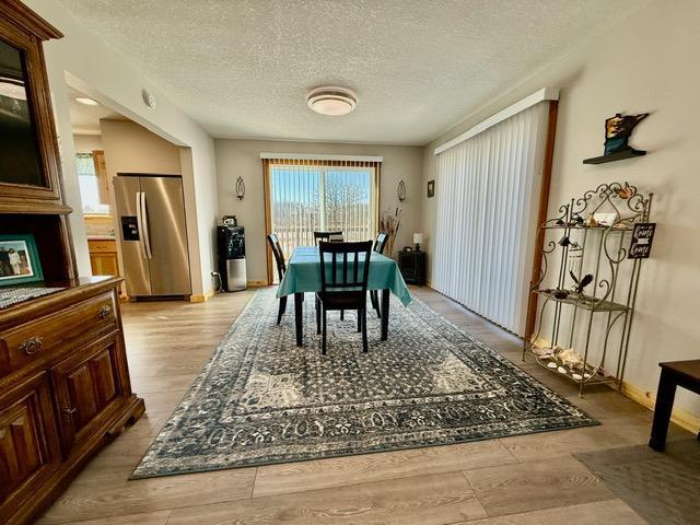 dining room with a textured ceiling and light wood-style flooring