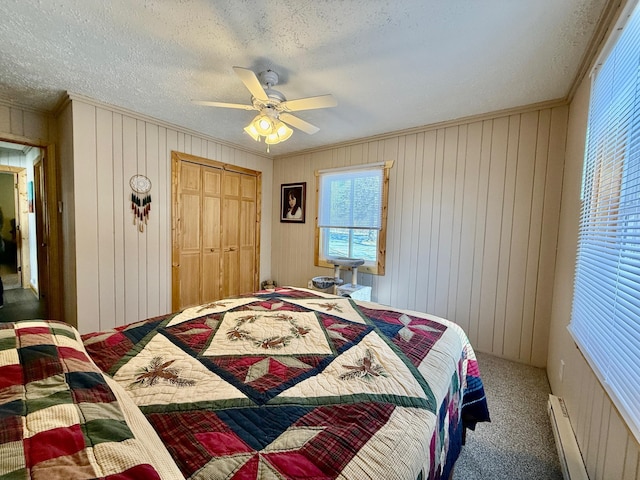 carpeted bedroom featuring crown molding, a closet, baseboard heating, ceiling fan, and a textured ceiling