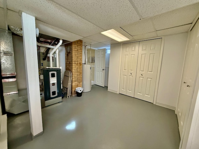 finished basement with a paneled ceiling and gas water heater