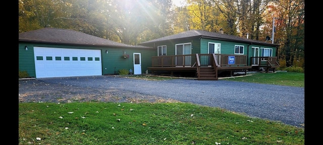 view of front facade featuring aphalt driveway, a front yard, a garage, and a wooden deck