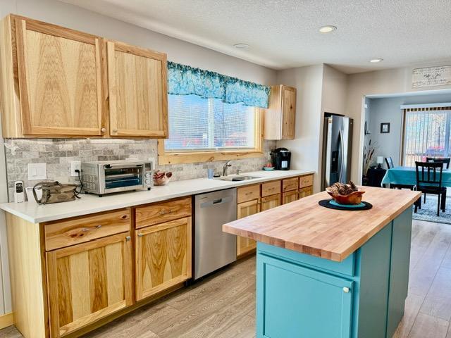 45936 State Highway 65, Mcgregor, MN 55760 - kitchen featuring stainless steel appliances, wooden counters, light wood finished floors, decorative backsplash, and a textured ceiling