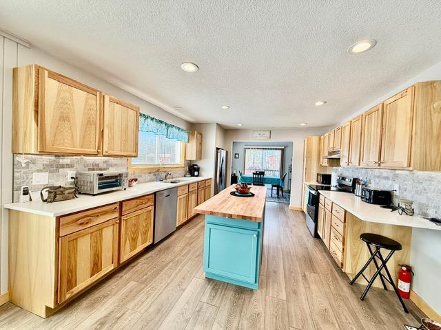 45936 State Highway 65, Mcgregor, MN 55760 - kitchen with appliances with stainless steel finishes, wood counters, light wood-style flooring, a textured ceiling, and backsplash