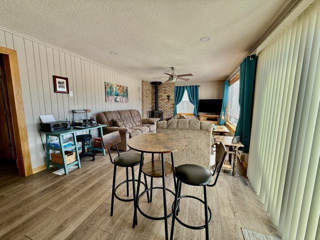 45936 State Highway 65, Mcgregor, MN 55760 - dining space featuring a wood stove, a textured ceiling, light wood-style flooring, and a ceiling fan