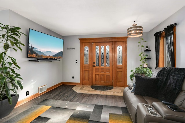 foyer entrance featuring baseboards, wood finished floors, visible vents, and a chandelier