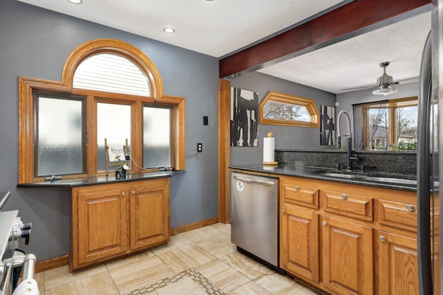 kitchen featuring a sink, brown cabinetry, baseboards, dishwasher, and ceiling fan