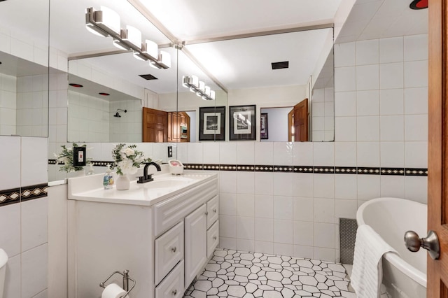 full bath featuring vanity, tile walls, a soaking tub, and tile patterned floors