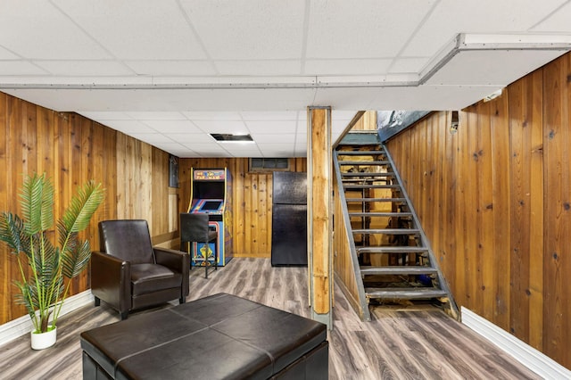 interior space featuring stairway, wood walls, a paneled ceiling, and wood finished floors